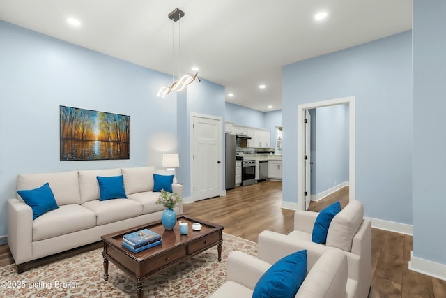 living area with baseboards, wood finished floors, and recessed lighting