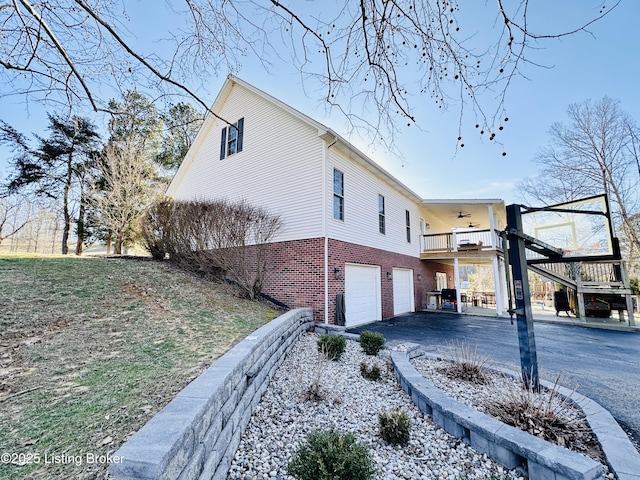 view of home's exterior with aphalt driveway, brick siding, stairway, ceiling fan, and a garage