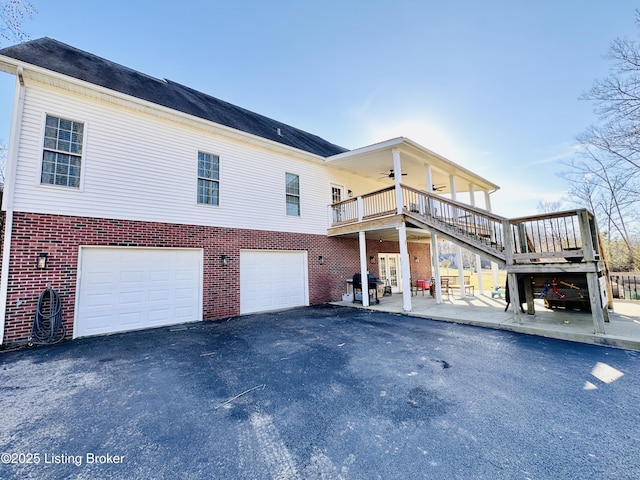 rear view of house with a patio, aphalt driveway, an attached garage, brick siding, and a ceiling fan