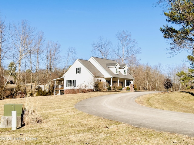 view of side of property with curved driveway and a lawn