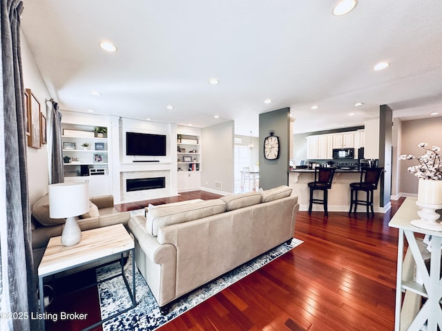 living area with recessed lighting, dark wood-style flooring, a fireplace, and baseboards