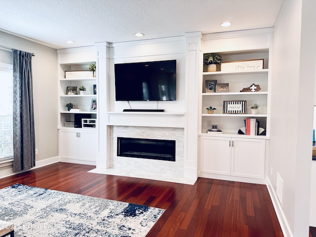 living room with a textured ceiling, a fireplace with flush hearth, dark wood finished floors, and visible vents