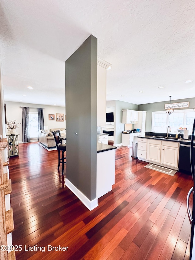 kitchen with dark countertops, white cabinets, dark wood-style flooring, and open floor plan