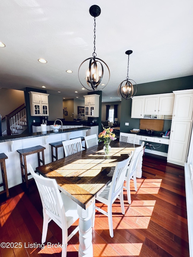 dining space featuring a chandelier, recessed lighting, dark wood-style flooring, and stairway