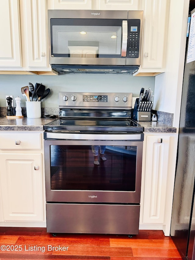 kitchen featuring white cabinetry, appliances with stainless steel finishes, and wood finished floors