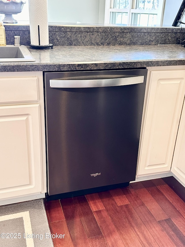 kitchen featuring dark countertops, white cabinets, dark wood finished floors, and stainless steel dishwasher