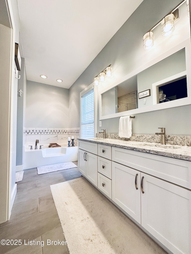 bathroom with double vanity, a sink, and a bath