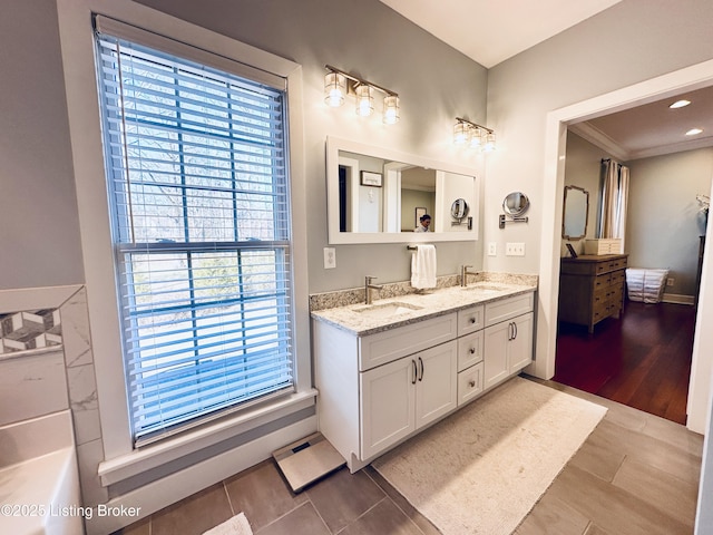 bathroom with crown molding, tile patterned flooring, a sink, and double vanity