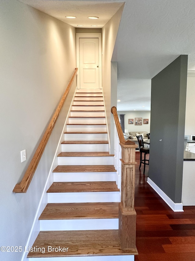 stairway with wood finished floors and baseboards