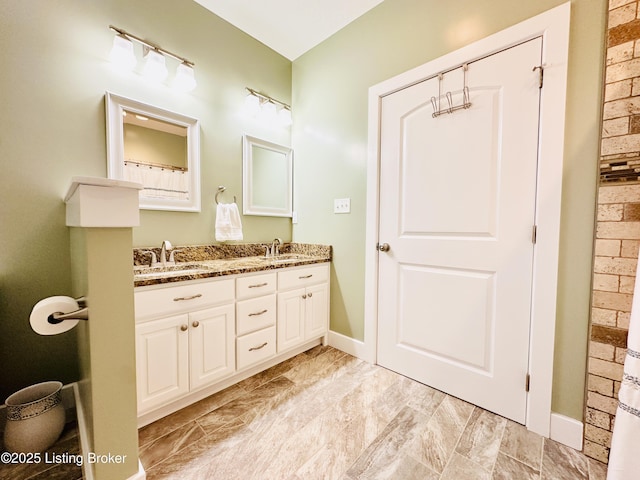 bathroom featuring double vanity, a sink, and baseboards