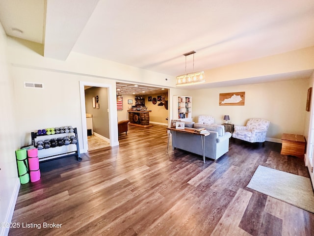 living area featuring baseboards, visible vents, and wood finished floors