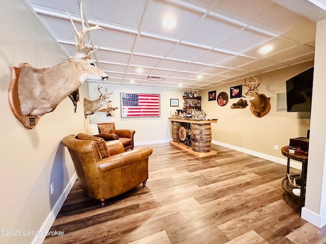 sitting room with a dry bar, visible vents, baseboards, and wood finished floors