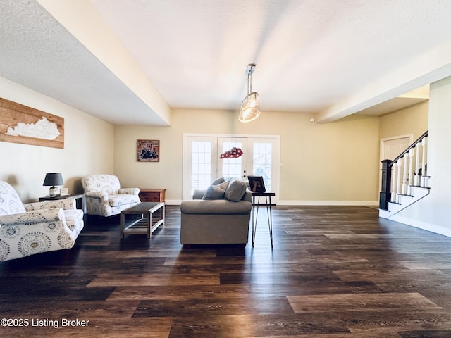 living area featuring a textured ceiling, dark wood-type flooring, baseboards, french doors, and stairway