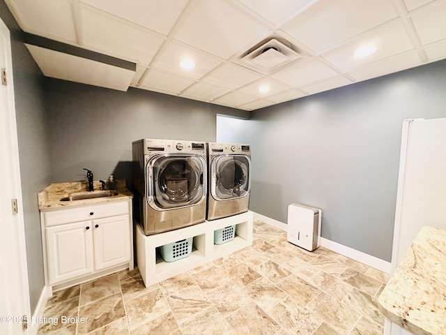 washroom featuring cabinet space, baseboards, visible vents, washer and clothes dryer, and a sink