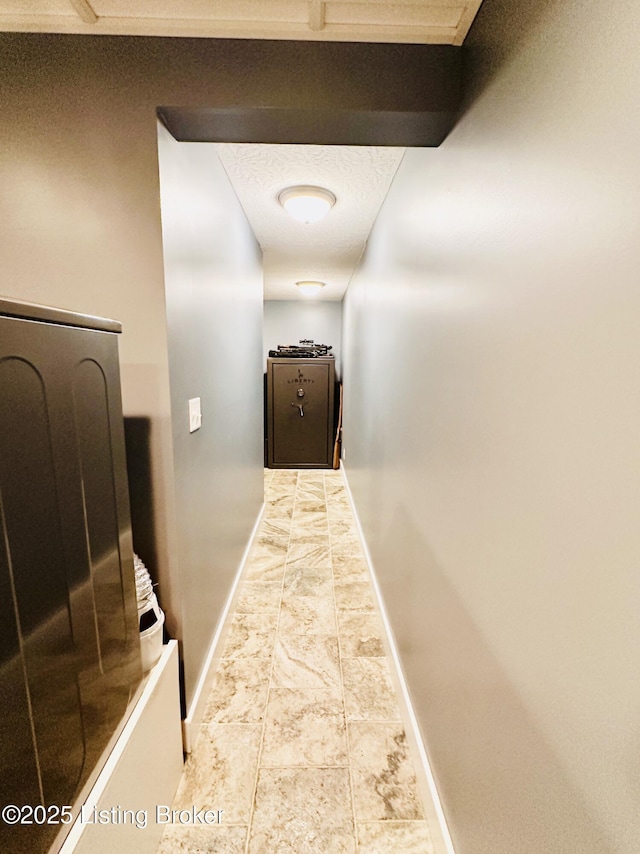 hallway with a textured ceiling and baseboards