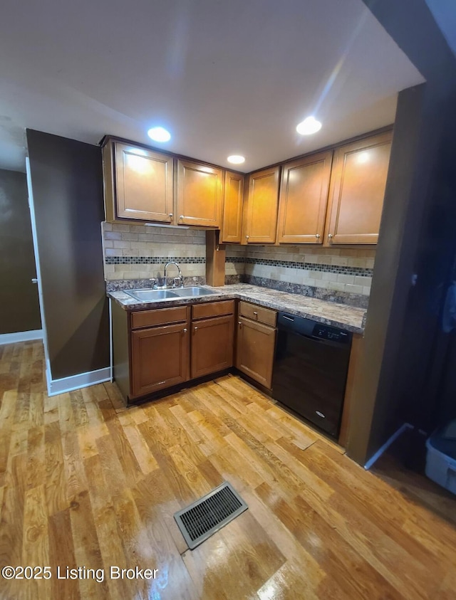 kitchen with dishwasher, visible vents, light wood finished floors, and a sink