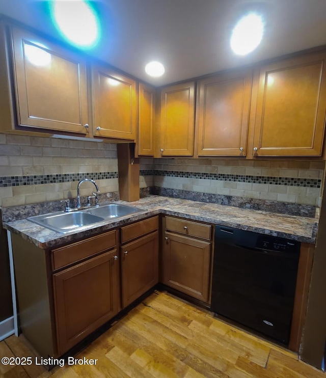 kitchen with light wood-style flooring, black dishwasher, backsplash, and a sink