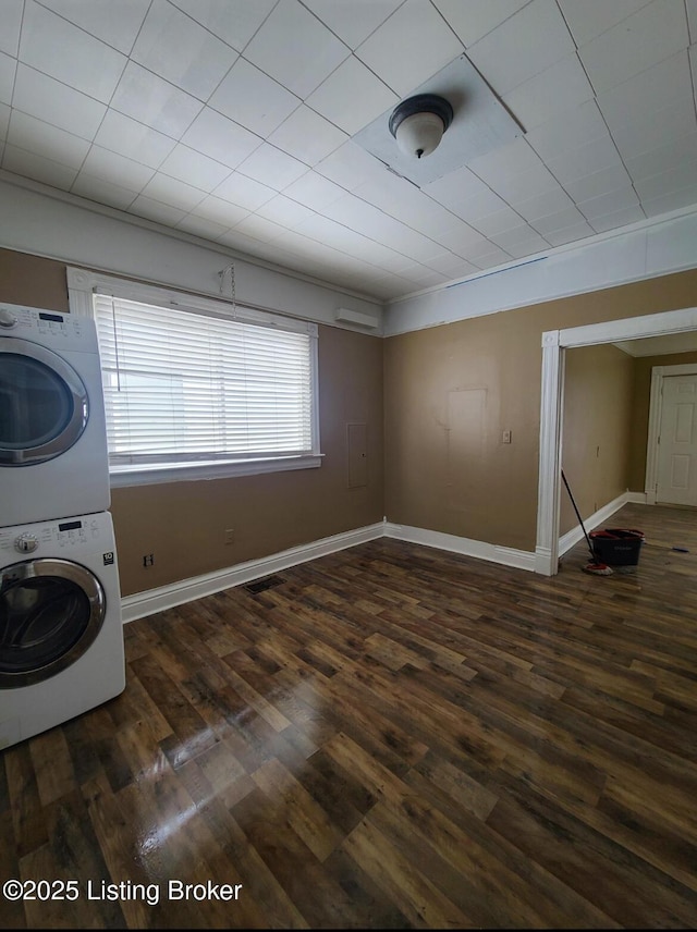 washroom featuring dark wood finished floors, laundry area, baseboards, and stacked washing maching and dryer