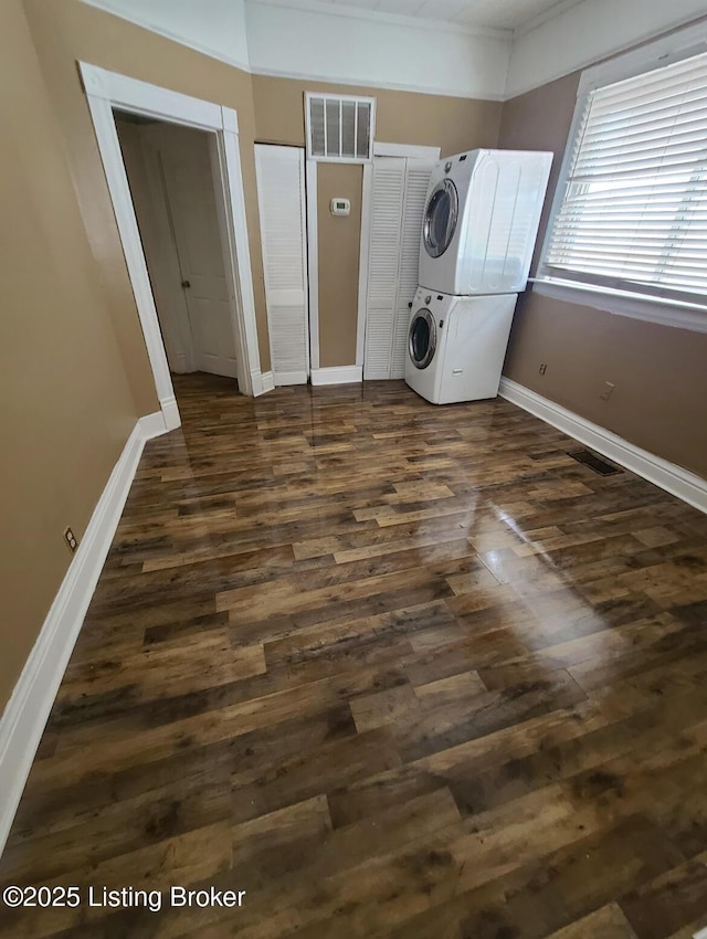 laundry room featuring baseboards, visible vents, dark wood finished floors, laundry area, and stacked washer and dryer