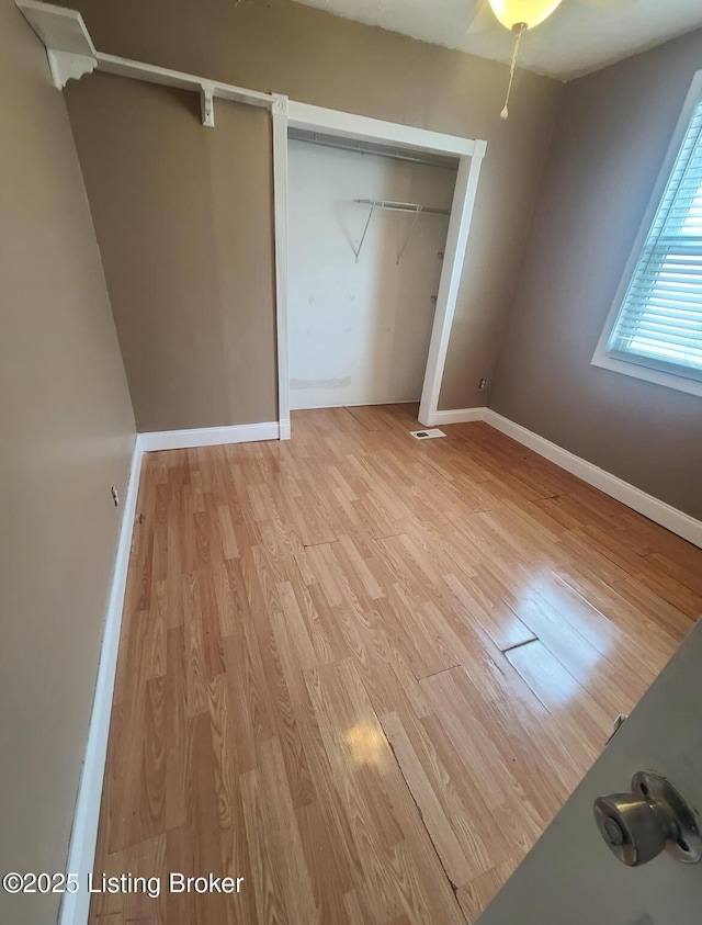 unfurnished bedroom featuring visible vents, baseboards, light wood-type flooring, and a closet