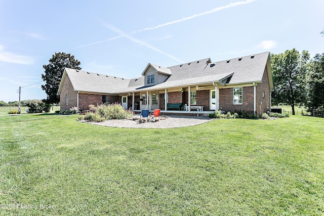 rear view of house with a yard, brick siding, a patio, and a shingled roof