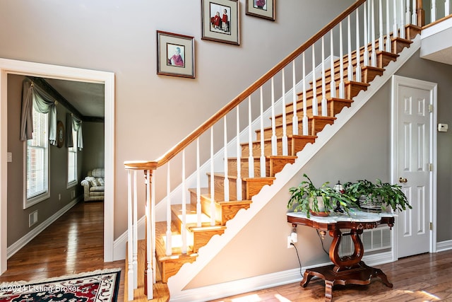 stairway with wood-type flooring, visible vents, and baseboards