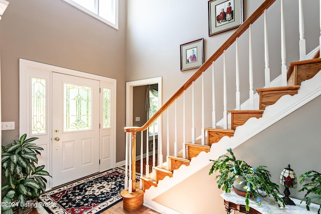 entryway featuring a high ceiling, stairway, and wood finished floors