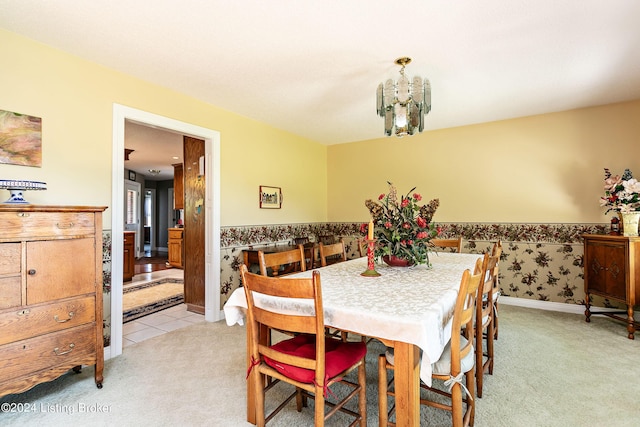 dining area featuring light carpet, a wainscoted wall, and a notable chandelier