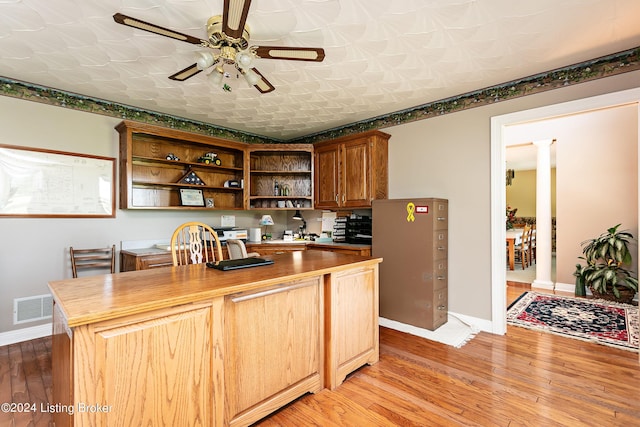 kitchen featuring visible vents, light wood-type flooring, a kitchen island, and decorative columns