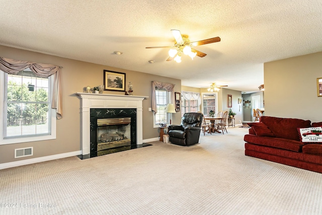 living room featuring ceiling fan, a fireplace, visible vents, baseboards, and carpet