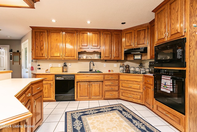 kitchen with a sink, under cabinet range hood, black appliances, and light tile patterned floors