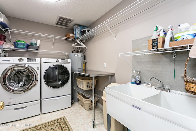 washroom featuring laundry area, visible vents, independent washer and dryer, a textured ceiling, and a sink