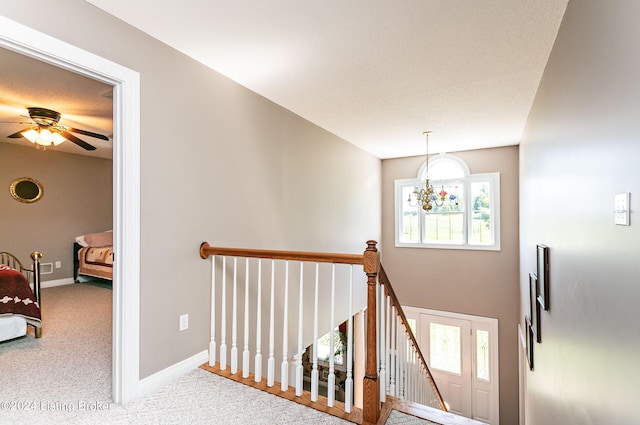 stairs featuring baseboards, carpet flooring, and ceiling fan with notable chandelier