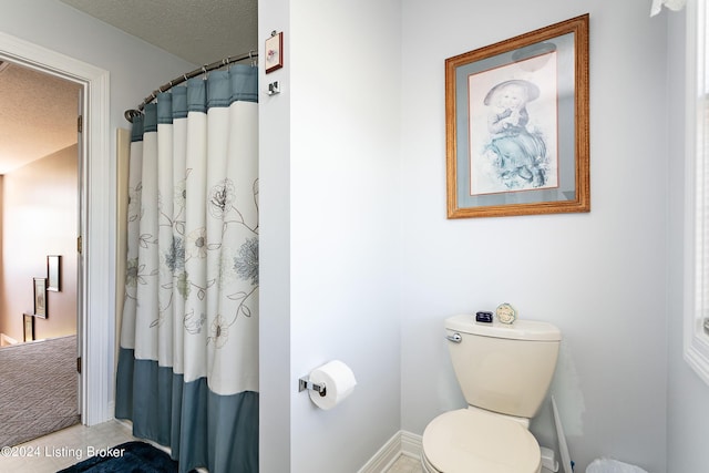 full bathroom featuring a textured ceiling, toilet, and a shower with curtain