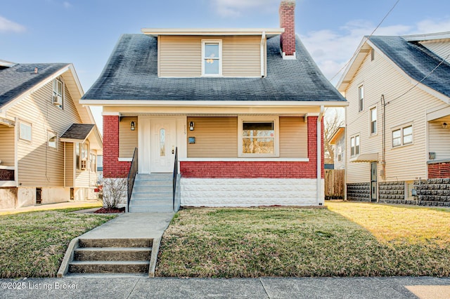 view of front of house featuring brick siding, a chimney, and a front lawn