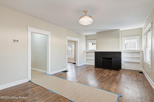 unfurnished living room featuring baseboards, wood-type flooring, and a brick fireplace