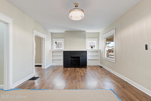 unfurnished living room with wood-type flooring, visible vents, and baseboards