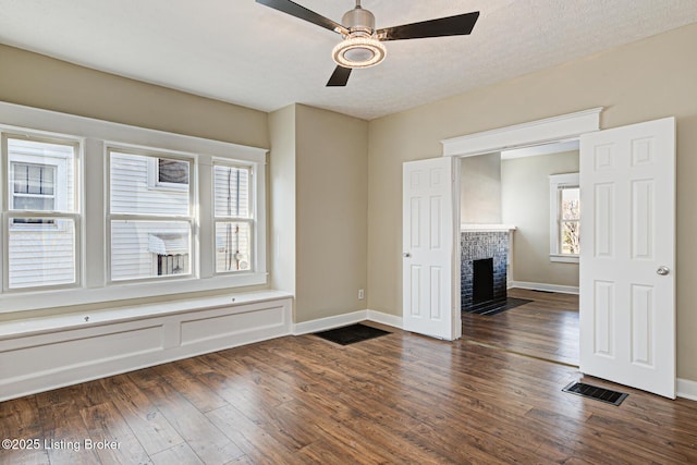 unfurnished living room featuring dark wood-type flooring, baseboards, a fireplace with flush hearth, and a ceiling fan