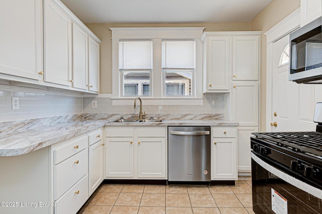 kitchen featuring appliances with stainless steel finishes, a sink, white cabinetry, backsplash, and light tile patterned flooring