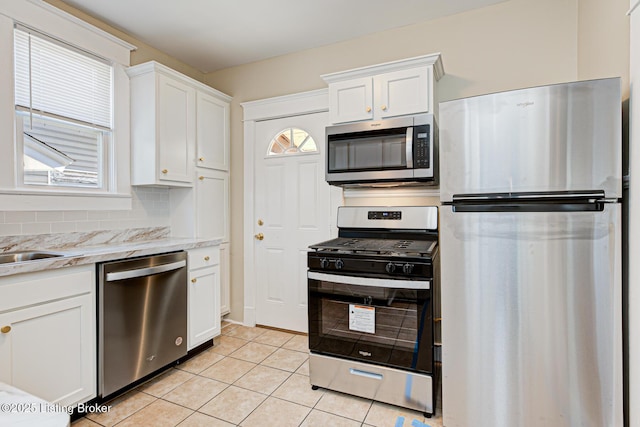 kitchen featuring light tile patterned floors, stainless steel appliances, tasteful backsplash, and white cabinetry