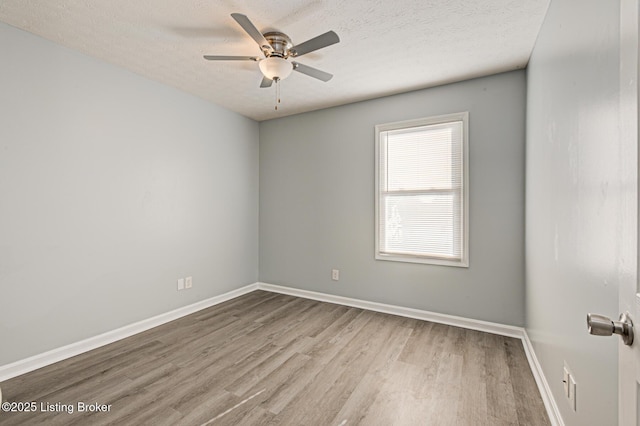 empty room with a ceiling fan, a textured ceiling, baseboards, and wood finished floors