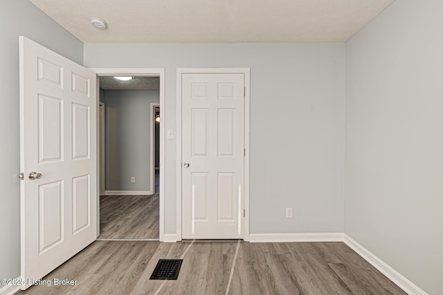 empty room featuring visible vents, baseboards, and wood finished floors