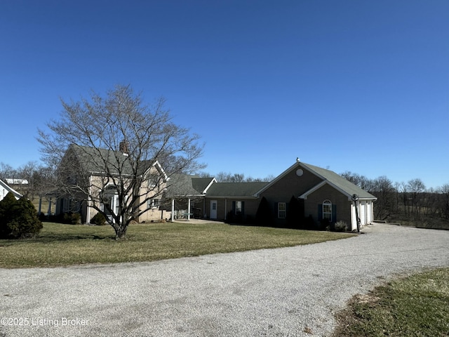 view of front of house featuring a front lawn and gravel driveway