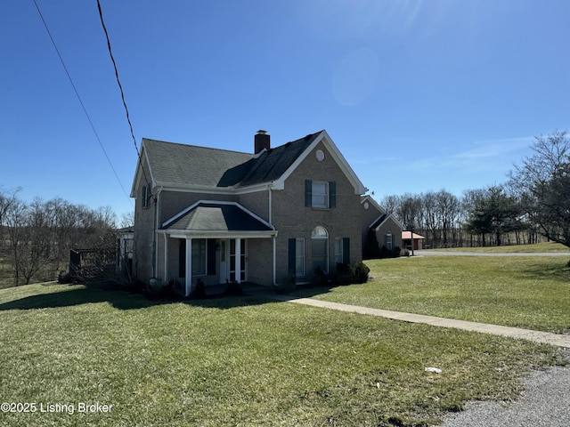 view of front of property with a front yard, brick siding, and a chimney