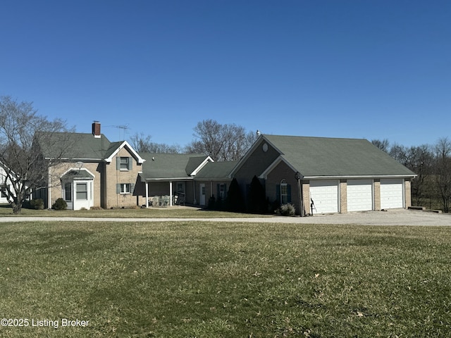 view of front of house with driveway, brick siding, a chimney, and a front yard