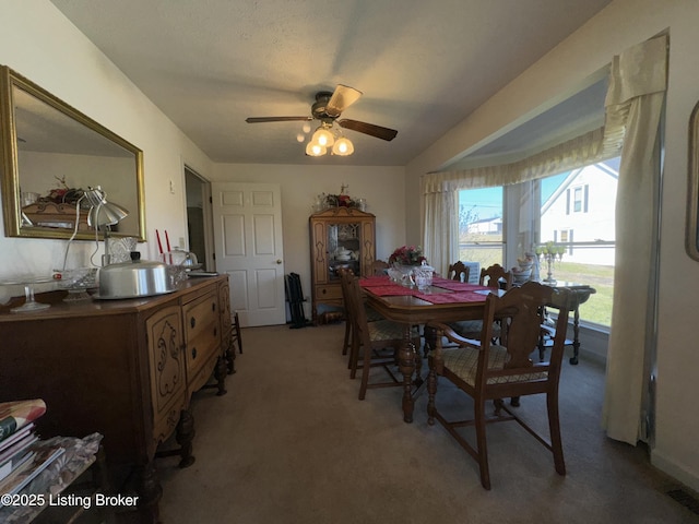 dining space featuring a ceiling fan and light colored carpet