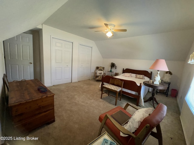 carpeted bedroom featuring multiple closets, lofted ceiling, and ceiling fan