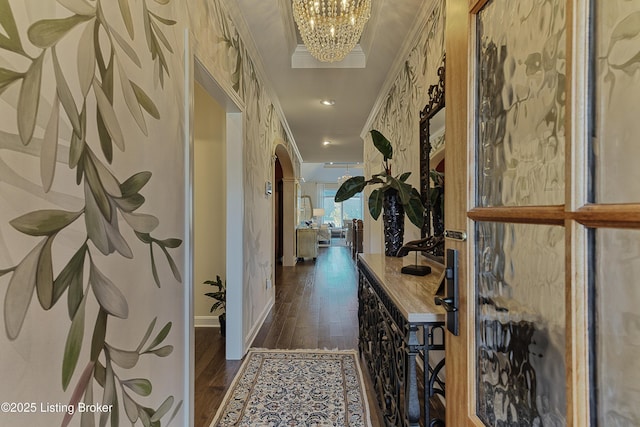 hallway with baseboards, an inviting chandelier, arched walkways, dark wood-style flooring, and ornamental molding