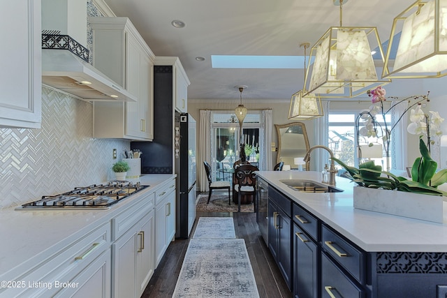 kitchen with a center island with sink, a sink, stainless steel appliances, white cabinets, and wall chimney exhaust hood