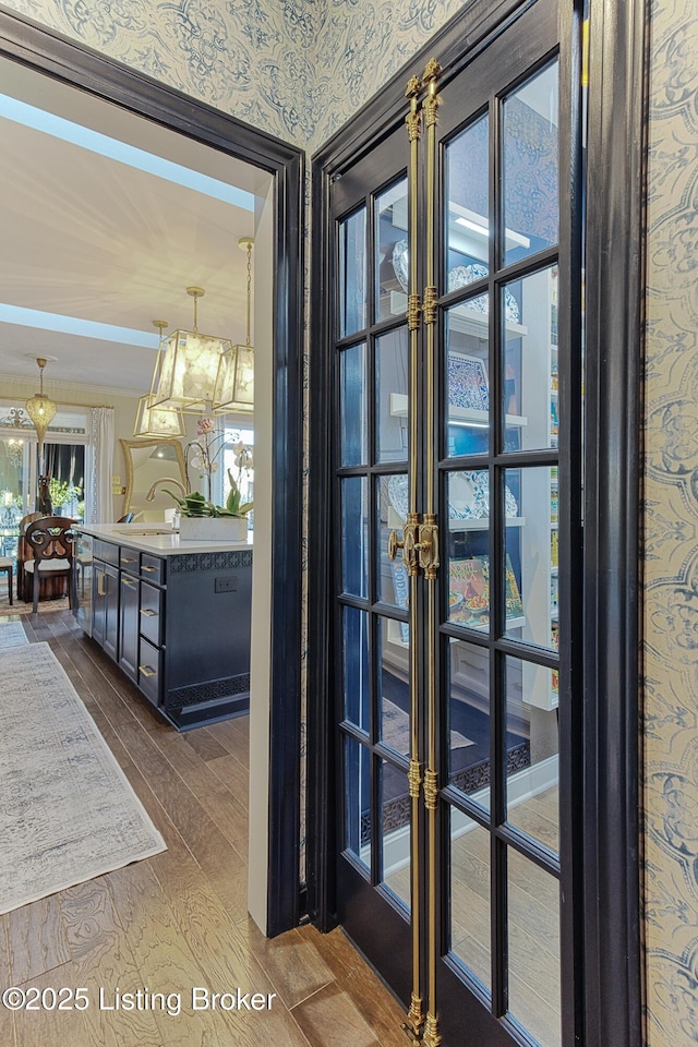 doorway to outside featuring a sink, french doors, wallpapered walls, and dark wood-style flooring